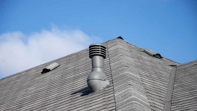 A sloped, shingle roof with two capped roof vents