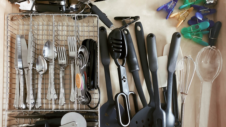 cluttered utensil drawer filled with flatware and kitchen utensils