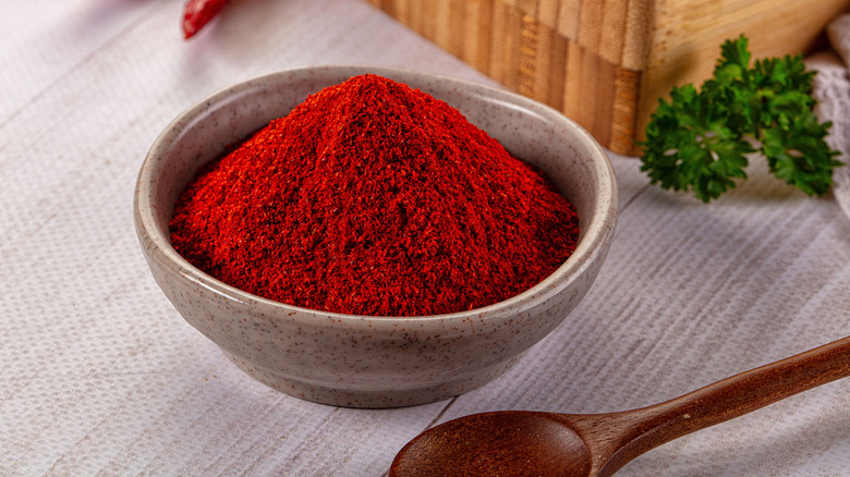 A bowl of chili powder next to a spoon