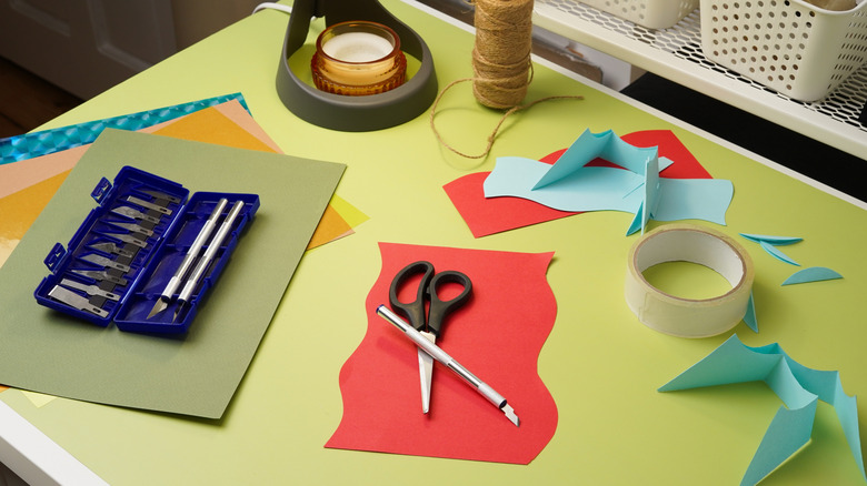 A yellow table with messy craft supplies on it.