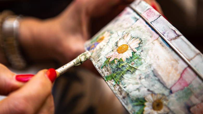 woman decorating tin using decoupage