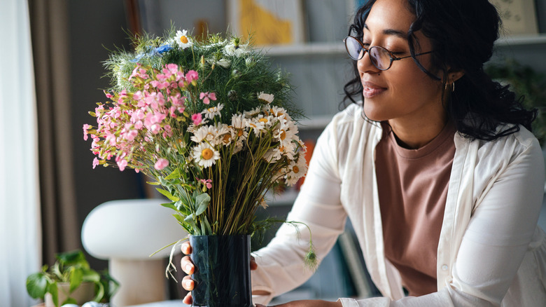 Young woman holds vase containing a bouquet of flowers