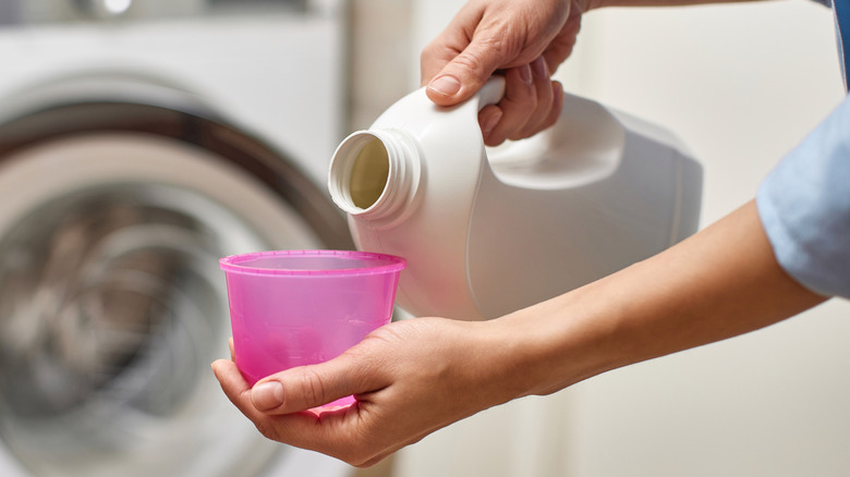 close up of person pouring laundry detergent into the lid