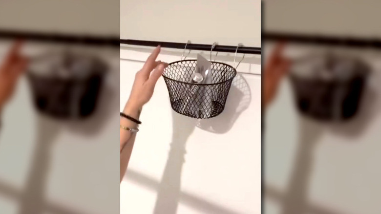 Closeup of person's hand reaching for bathroom supplies in a basket