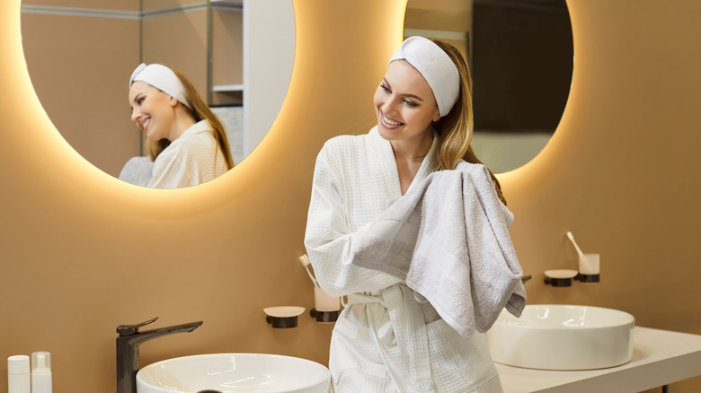 Smiling woman in robe drying hair in bathroom