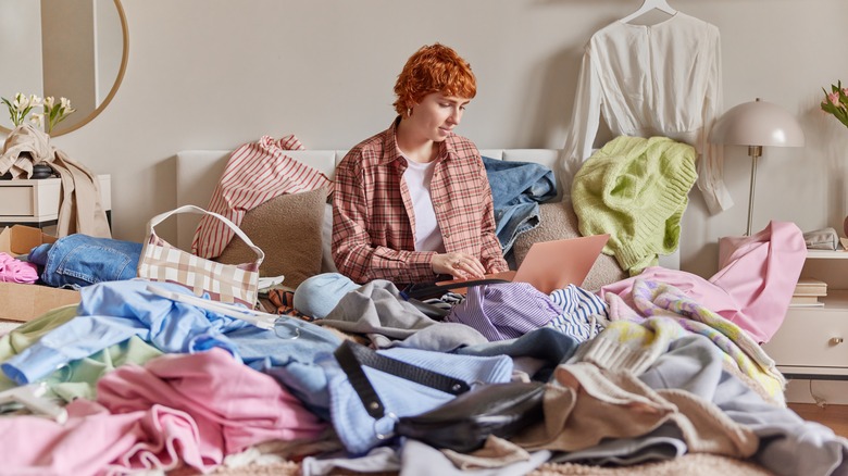 woman sits on messy bed 