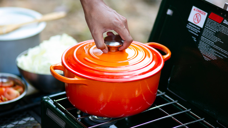 hand grabbing dutch oven lid