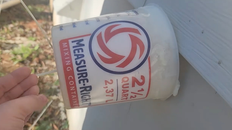 Spray foam inside a plastic mixing container placed over outdoor faucet