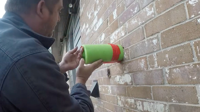 Person covering outdoor faucet with pool noodle