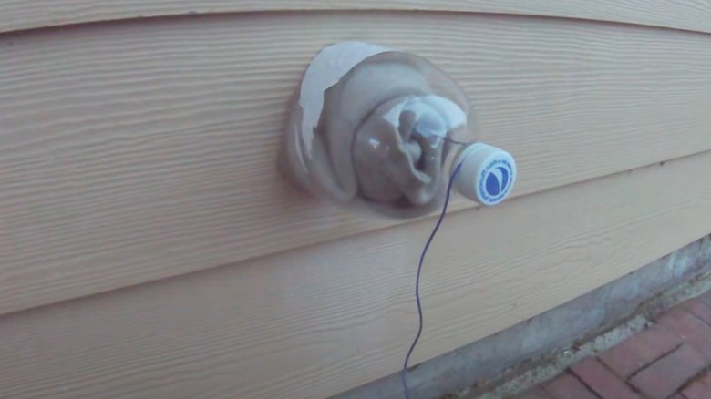 Socks and half of a soda bottle covering an outdoor faucet