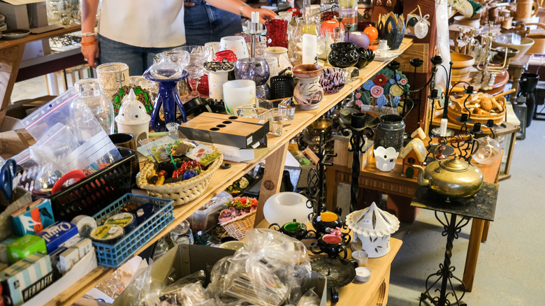 A cluttered store with trinkets and miscellaneous items, glassware displayed on a shelf