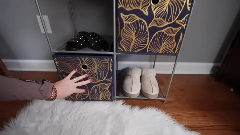 A metal shoe rack with fabric storage cubes and shoes