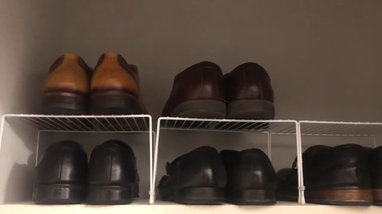Mens shoes on white shelf risers in a closet