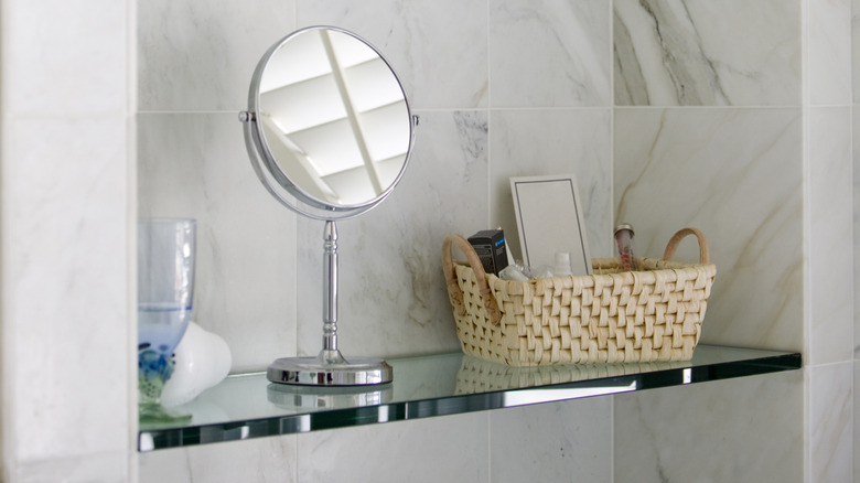 Mirror and a basket on a glass shelf in a bathroom