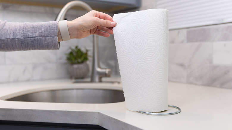 Hand tearing paper towel from a roll in the kitchen