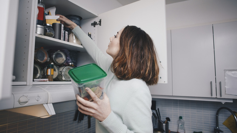 Woman searching for items in kitchen cabinet