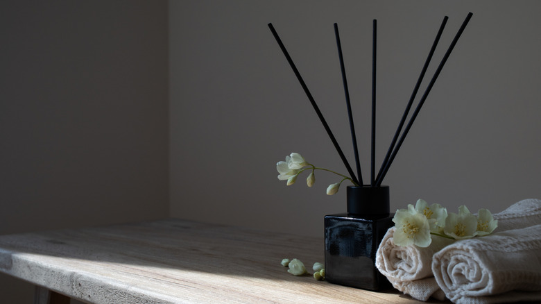A reed diffuser sitting next to some rolled up towels