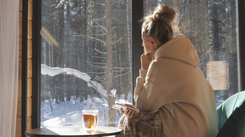 Woman staring out of a window on sunny winter day