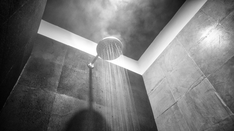 A black and white photo of water coming out of a shower head with steam rising