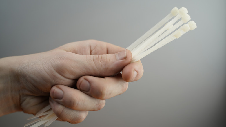 A hand holding a bundle of white zip ties