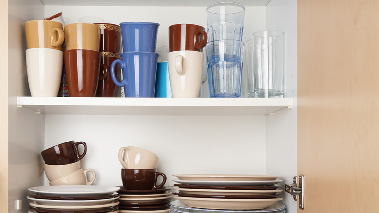 kitchen cabinet full of stacked mugs