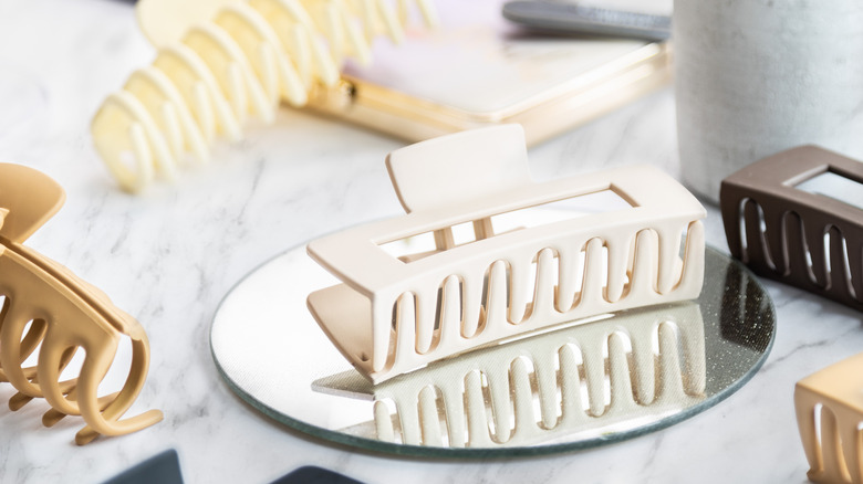 Different hair claw clips scattered on top of a table with a mirror and other items.