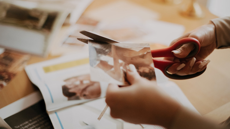 A person cuts magazine clippings with scissors for a collage