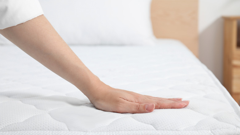 Woman with hand on clean white mattress
