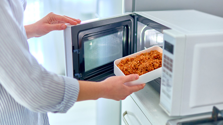 Person putting food in microwave