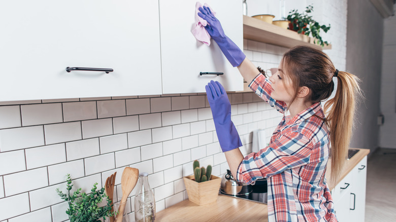 Woman cleaning white cabinet doors