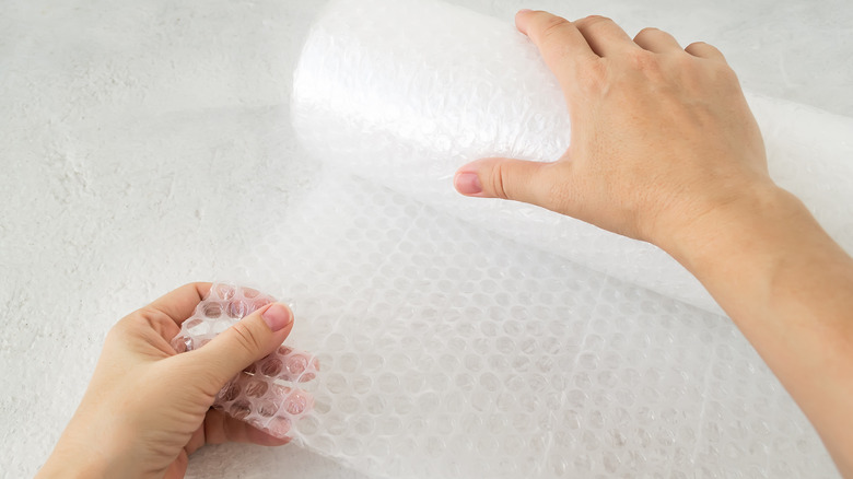 Hands unrolling bubble wrap roll