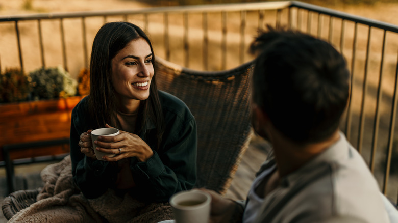 a couple sitting on deck furniture enjoying warm beverages