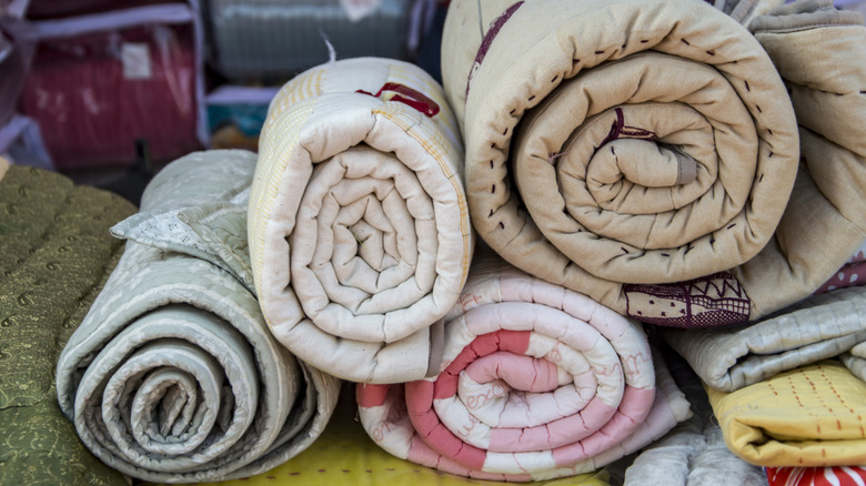 Rolled quilts in messy room