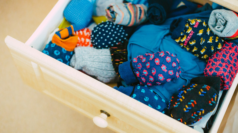 Open drawer messily packed with colorful socks and underwear