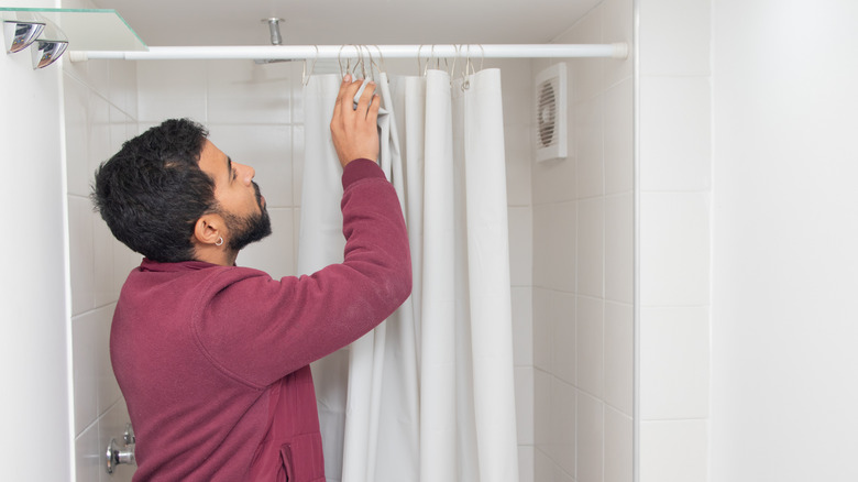 A man fitting a tension shower rod in an alcove