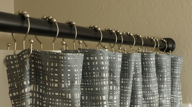 A gray and white shower curtain held up by a tension rod
