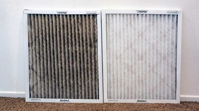 A dirty HVAC air filter sitting beside a clean new one