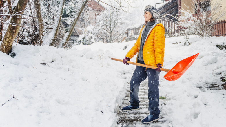 A woman shoveling snow on walkway