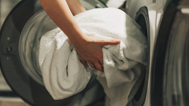 Close-up of a person taking white towels outs of a dryer