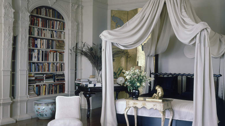 Vintage bedroom with original architecture, trim and molding, canopy bed, and vintage seating and bookcase.