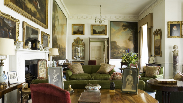 Historical interior architecture. Vintage paintings throughout the walls, drapery, and green sofa.