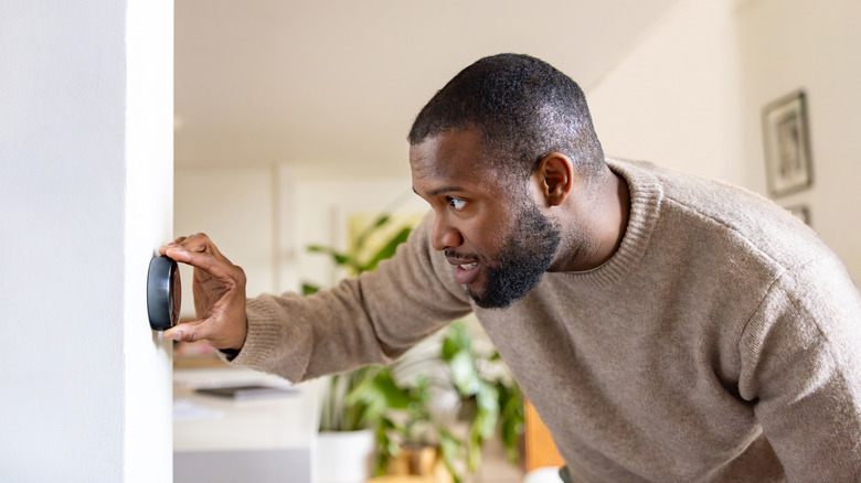 Hand reaching for smart thermostat