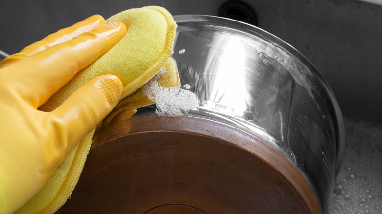 gloved hand cleaning old pot