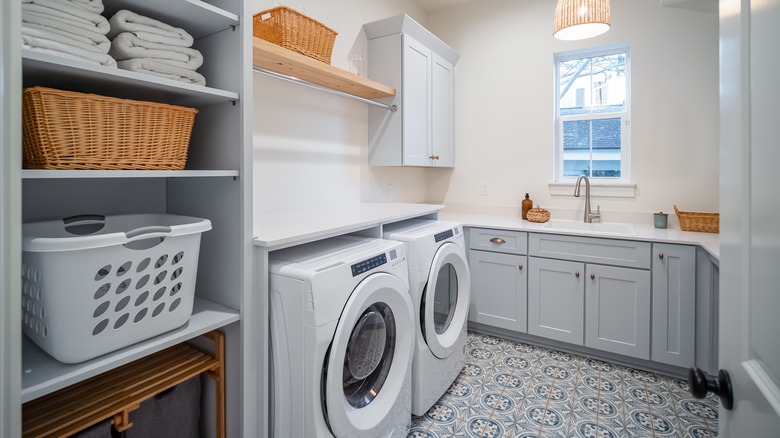 A large laundry room features a sink, folding station, and shelves with large baskets.