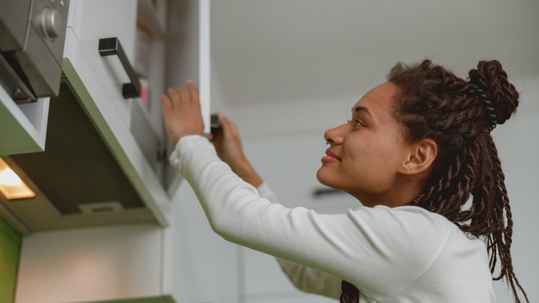 woman reaching into kitchen cabinet