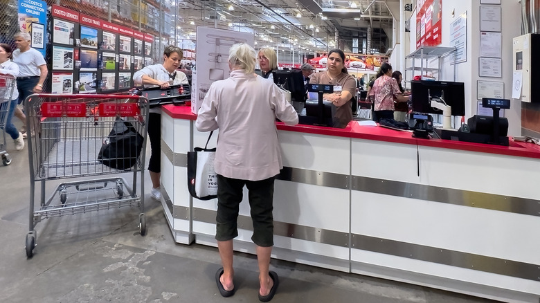 Customers standing and Costco employees working at a returns counter in the store.