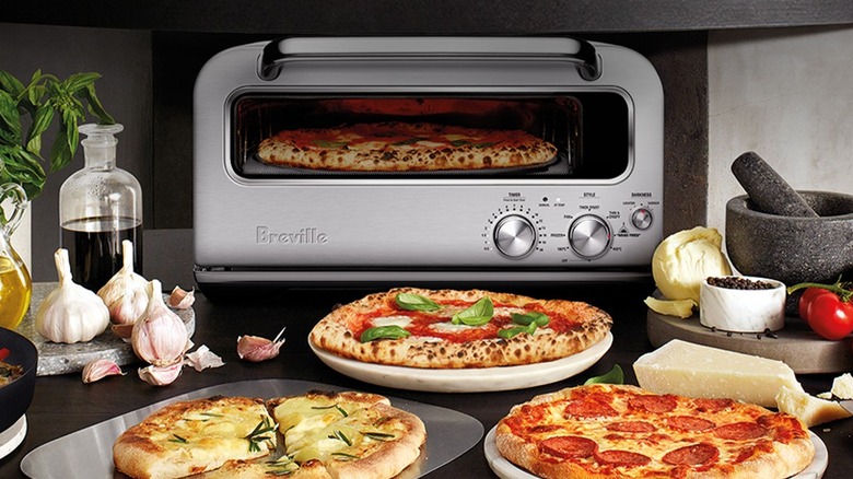 Breville countertop pizza oven among pizza ingredients and baked pizzas