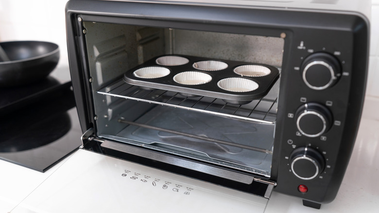 A muffin tray inside a black toaster oven