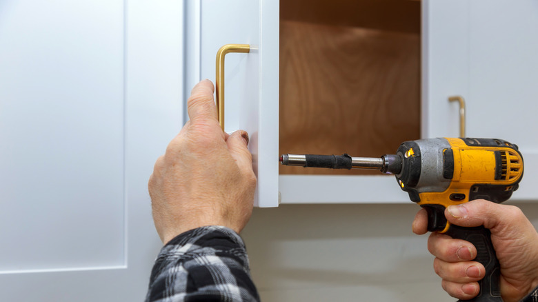 The installing a furniture handle process of assembling kitchen cabinet