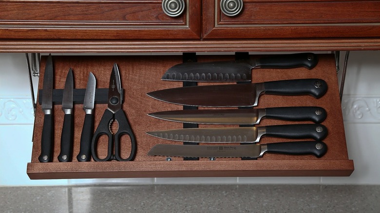 A pull-out kitchen block attached underneath a dark wood cabinet.